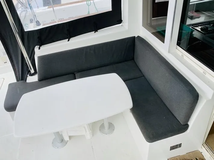 Unicorn Yacht Photos Pics Cozy seating area on a 2019 Lagoon 40 catamaran with a white table and dark cushions.