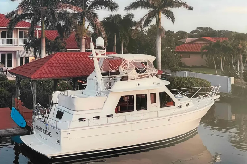 Free Ride Yacht Photos Pics 2002 President Trawler yacht docked by a waterfront home with palm trees.