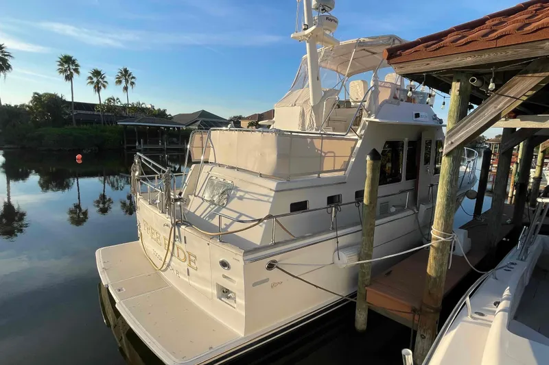 Free Ride Yacht Photos Pics 2002 President Trawler docked by a serene waterfront with palm trees.