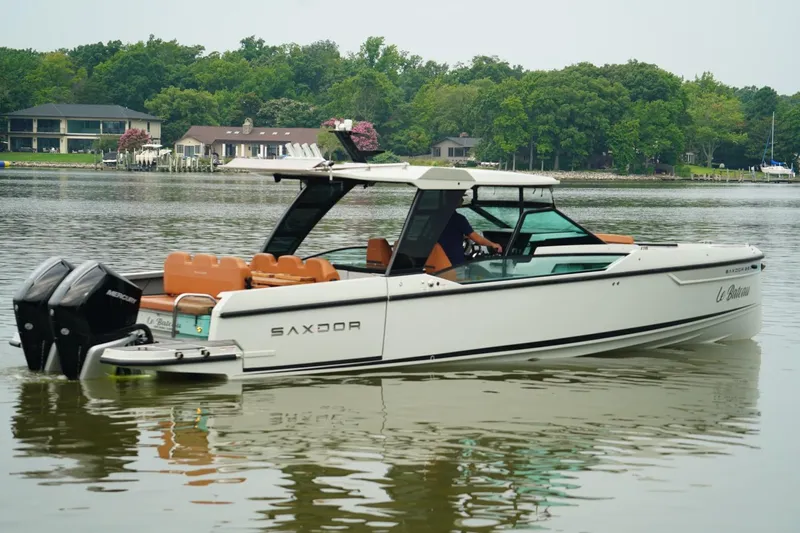  Yacht Photos Pics 2023 Saxdor 320 GTO boat on calm water, surrounded by lush greenery and waterfront homes.