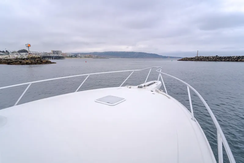 Champion Yacht Photos Pics Bow view of 2022 Viking 38 Open Billfish navigating calm waters near a rocky shoreline.