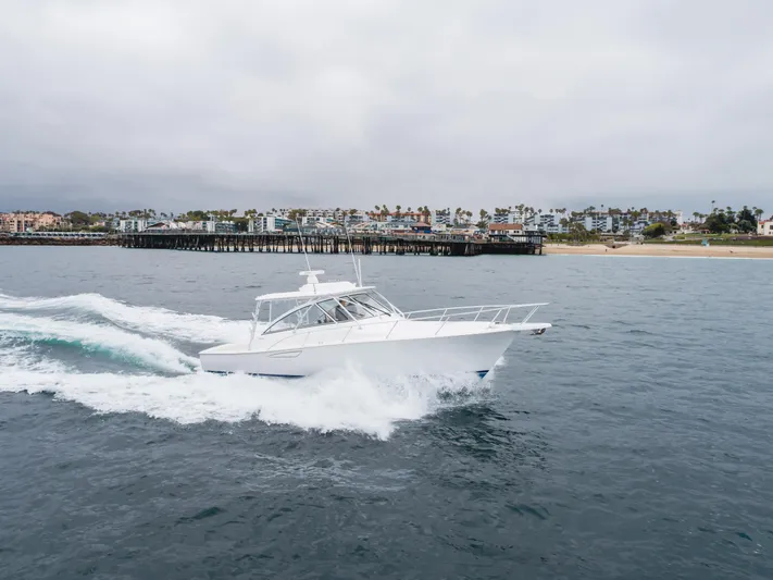 Champion Yacht Photos Pics 2022 Viking 38 Open Billfish cruising near a coastal pier under cloudy skies.