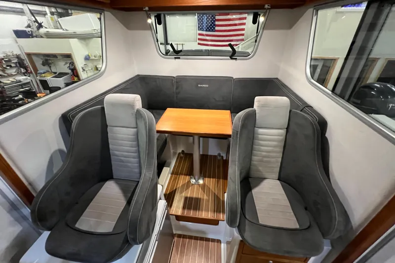  Yacht Photos Pics Interior of 2021 Sargo 25 boat with seating and table, American flag in background.