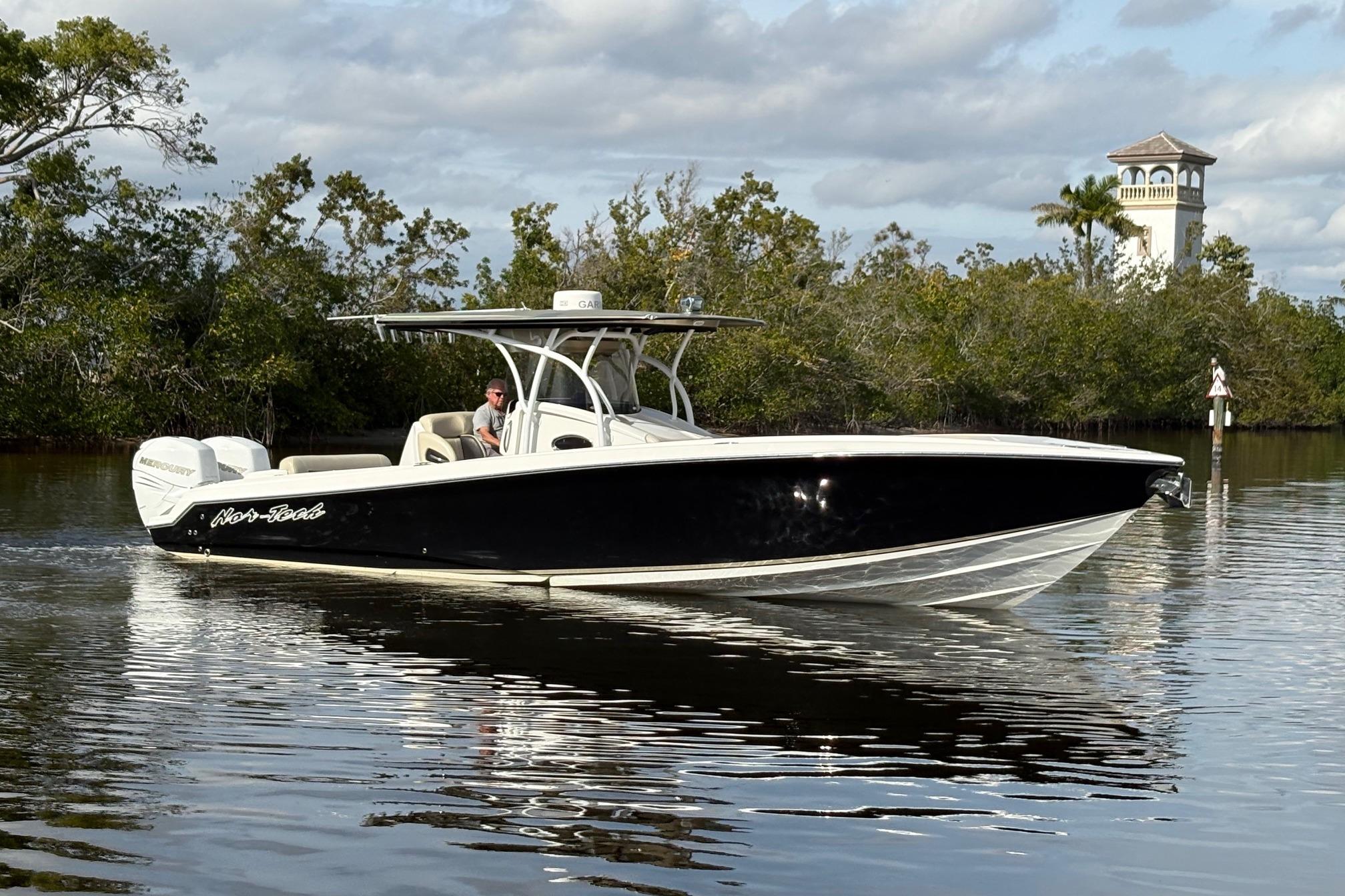 2012 Nor-Tech 340 Sport Center Console boat cruising on calm water, surrounded by lush greenery.