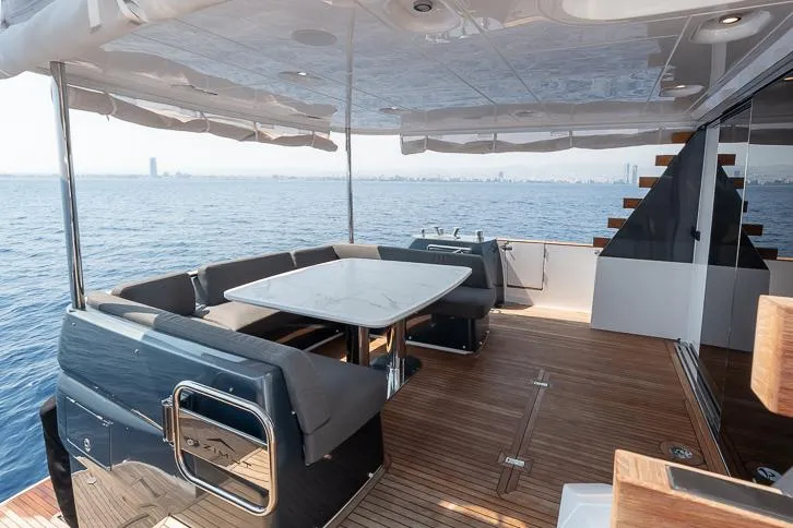 Grey T Yacht Photos Pics Luxurious Azimut Magellano 66 yacht deck with seating, table, and ocean view, 2021 model.