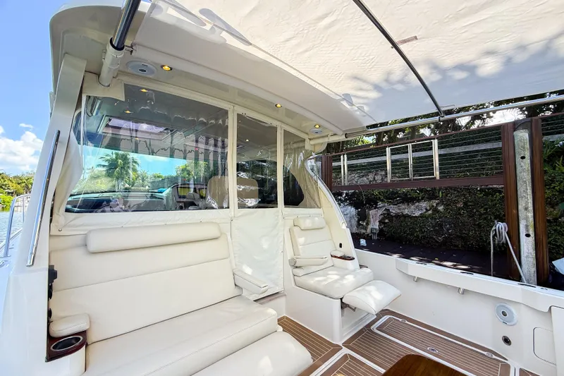  Yacht Photos Pics 2021 Hinckley Sport Boats 40x interior with white seating and canopy, docked by lush greenery.