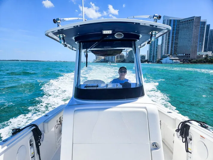  Yacht Photos Pics 2023 Edgewater 262CC boat cruising on blue waters near city skyline.