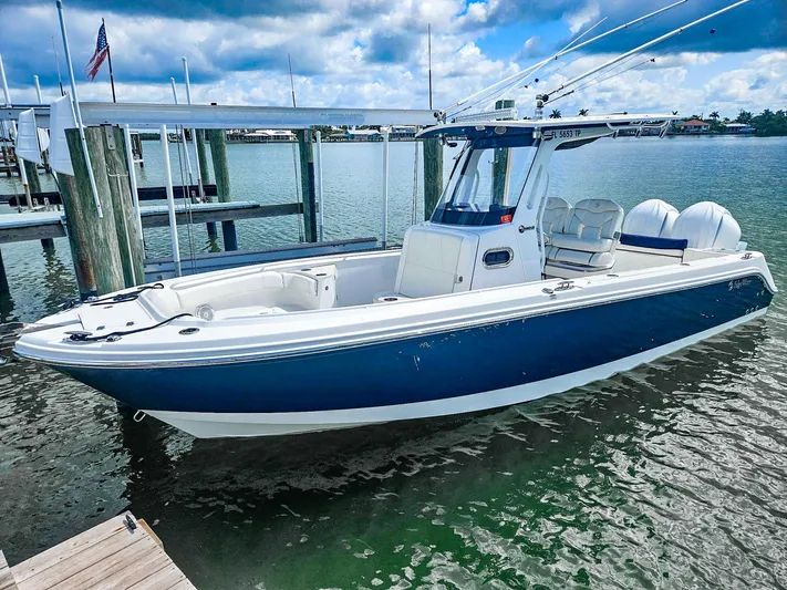  Yacht Photos Pics 2023 Edgewater 262CC boat docked, featuring sleek design and dual engines, under a partly cloudy sky.