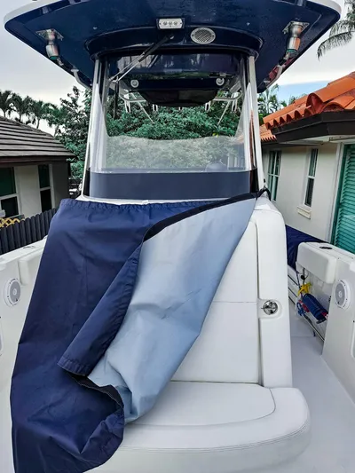  Yacht Photos Pics 2023 Edgewater 262CC boat with protective cover, docked near residential area.