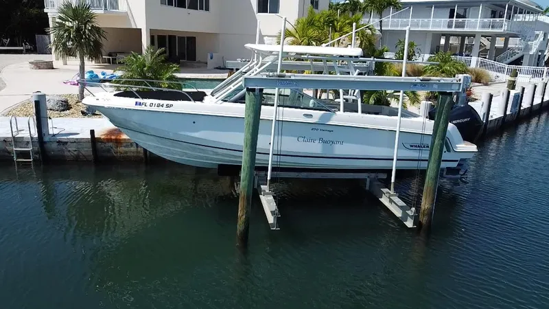  Yacht Photos Pics 2019 Boston Whaler 270 Vantage boat on lift at dockside, surrounded by waterfront homes.