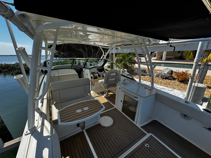  Yacht Photos Pics 2019 Boston Whaler 270 Vantage boat interior with seating and helm, docked by the water.