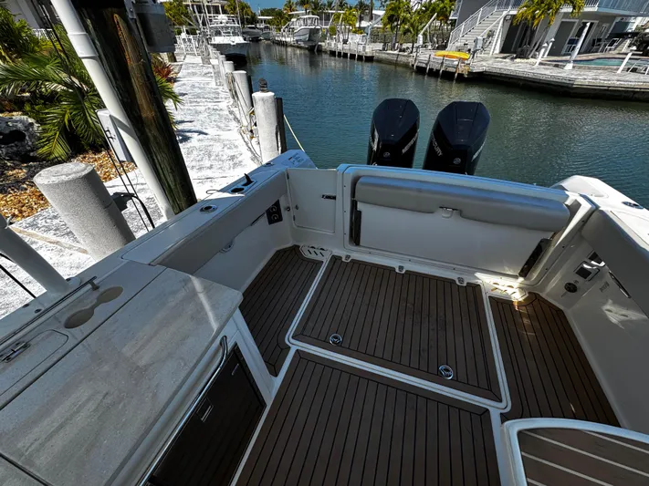  Yacht Photos Pics 2019 Boston Whaler 270 Vantage boat interior with wooden deck, docked by a canal.
