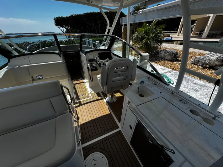  Yacht Photos Pics 2019 Boston Whaler 270 Vantage boat interior with seating and helm, docked by the shore.