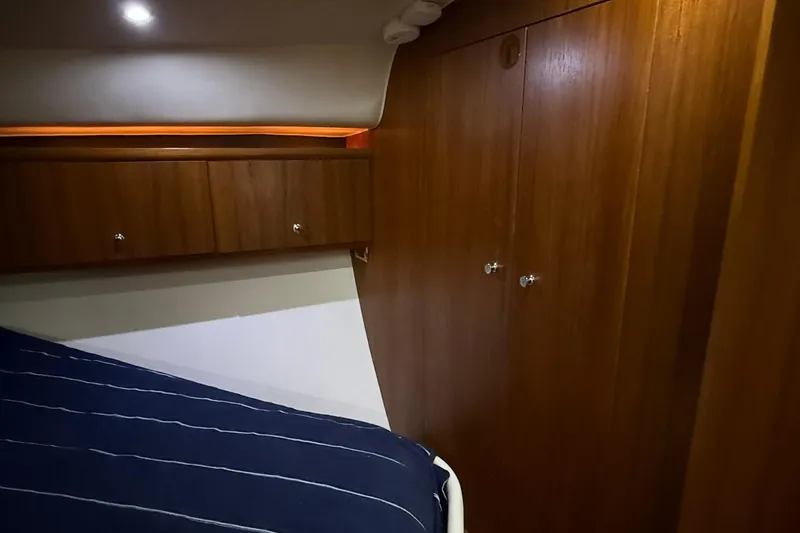  Yacht Photos Pics 2011 Tiara Yachts 4500 Sovran cabin interior with wooden cabinetry and striped bedding.