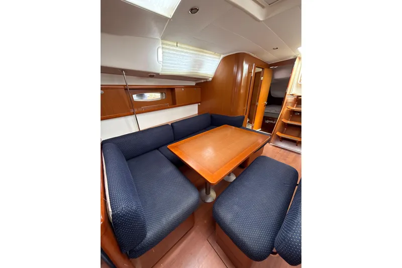 Vision 360 Yacht Photos Pics Interior of 2012 Beneteau First 435 sailboat with wooden table and blue seating.