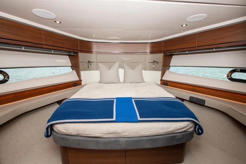 Wheelhouse Yacht Photos Pics Luxurious bedroom interior of 2021 Princess S66 yacht with elegant wood finishes and blue blanket.