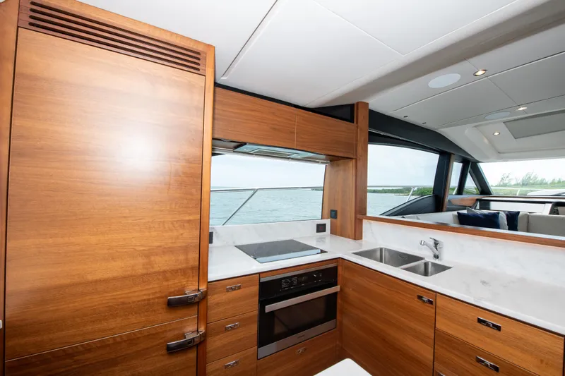 Wheelhouse Yacht Photos Pics Luxurious kitchen interior of 2021 Princess S66 yacht with wooden cabinetry and modern appliances.