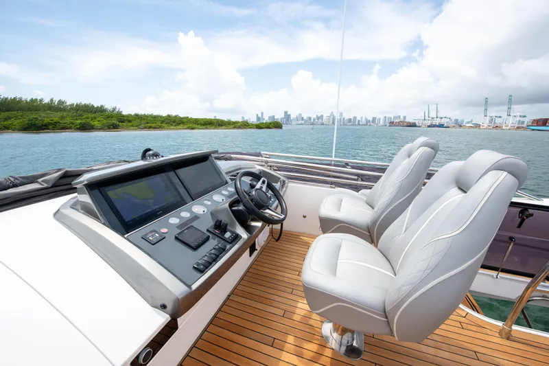 Wheelhouse Yacht Photos Pics 2021 Princess S66 yacht helm with dual seats, overlooking scenic waterfront and city skyline.
