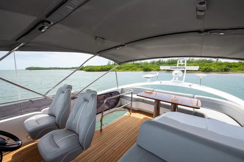 Wheelhouse Yacht Photos Pics Luxurious 2021 Princess S66 yacht interior with seating and table, overlooking serene waters.