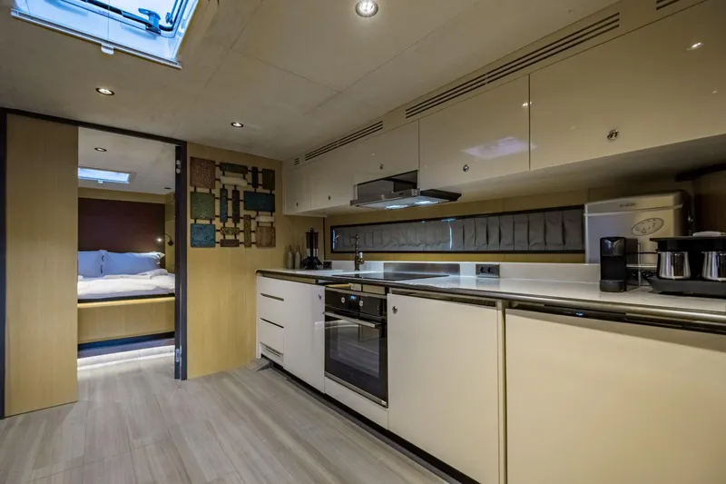  Yacht Photos Pics Modern yacht kitchen interior with sleek cabinetry, appliances, and a cozy bedroom view. Phantom Spook Fly 62, 2026.