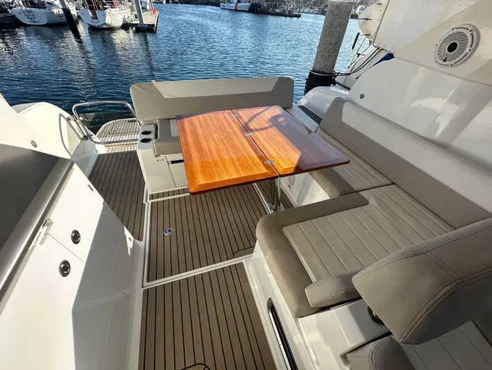 Le Bon Vie Yacht Photos Pics 2016 Jeanneau Leader 36 yacht deck with seating and wooden table by the water.