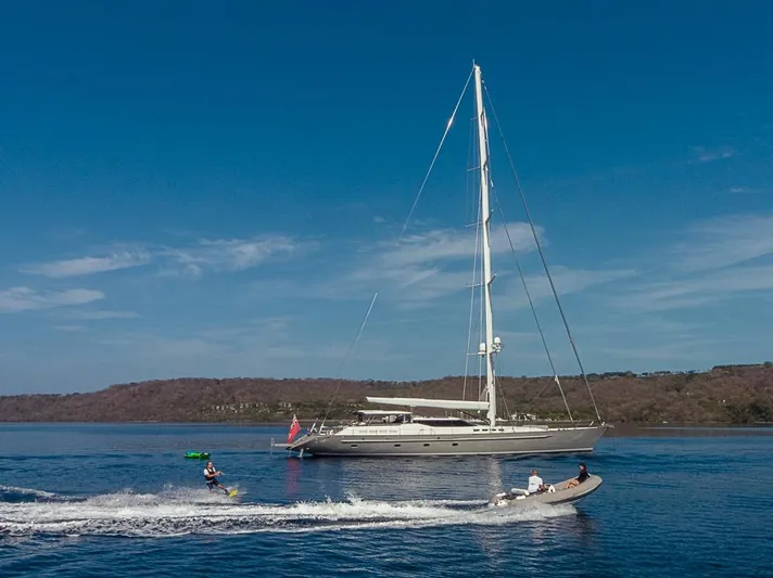 My Star Yacht Photos Pics Sailing yacht Alloy Yachts Sloop 1994 with people wakeboarding nearby on a sunny day.