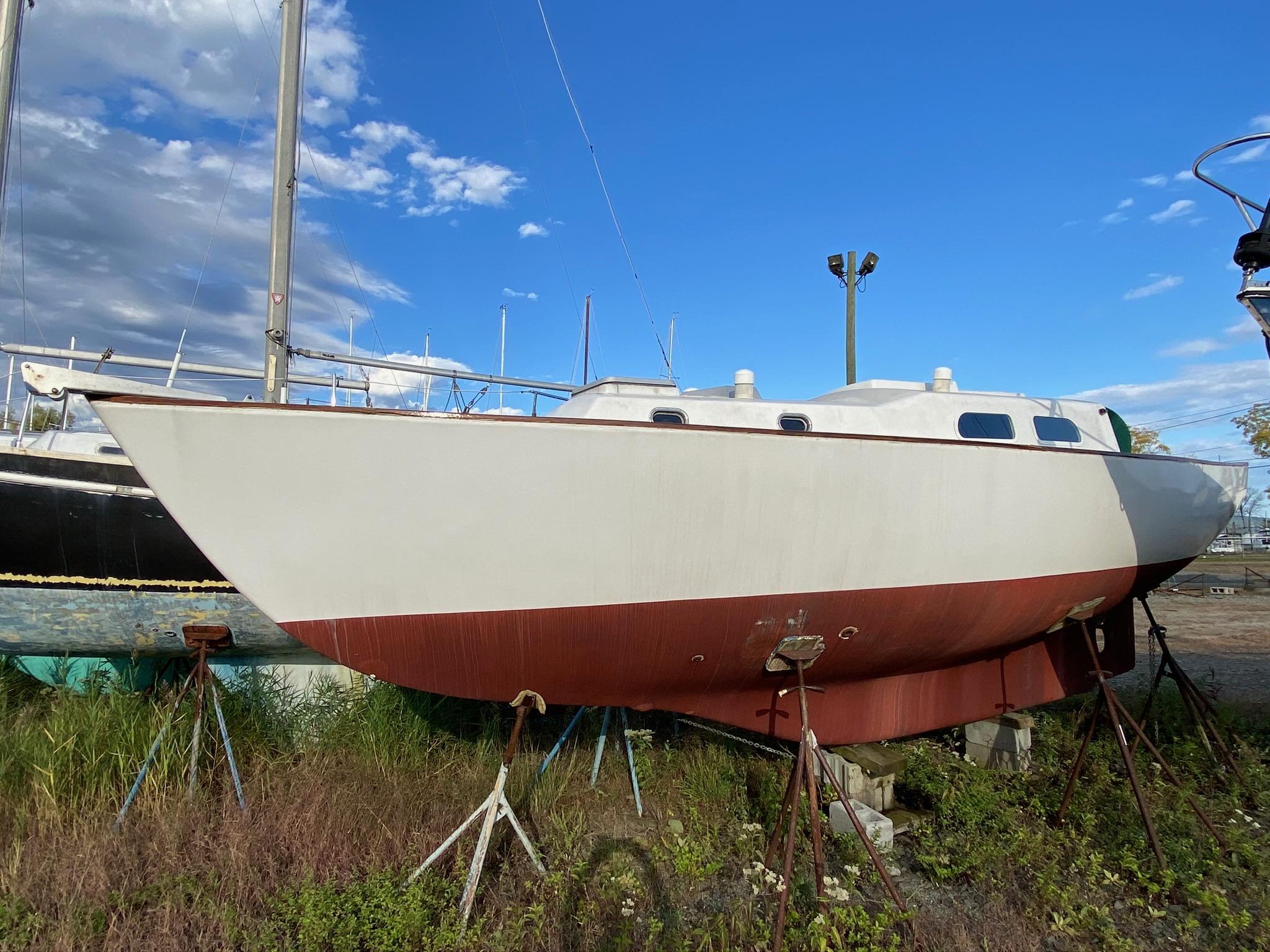 1968 Pearson Wanderer sailboat on stands, under a clear blue sky.