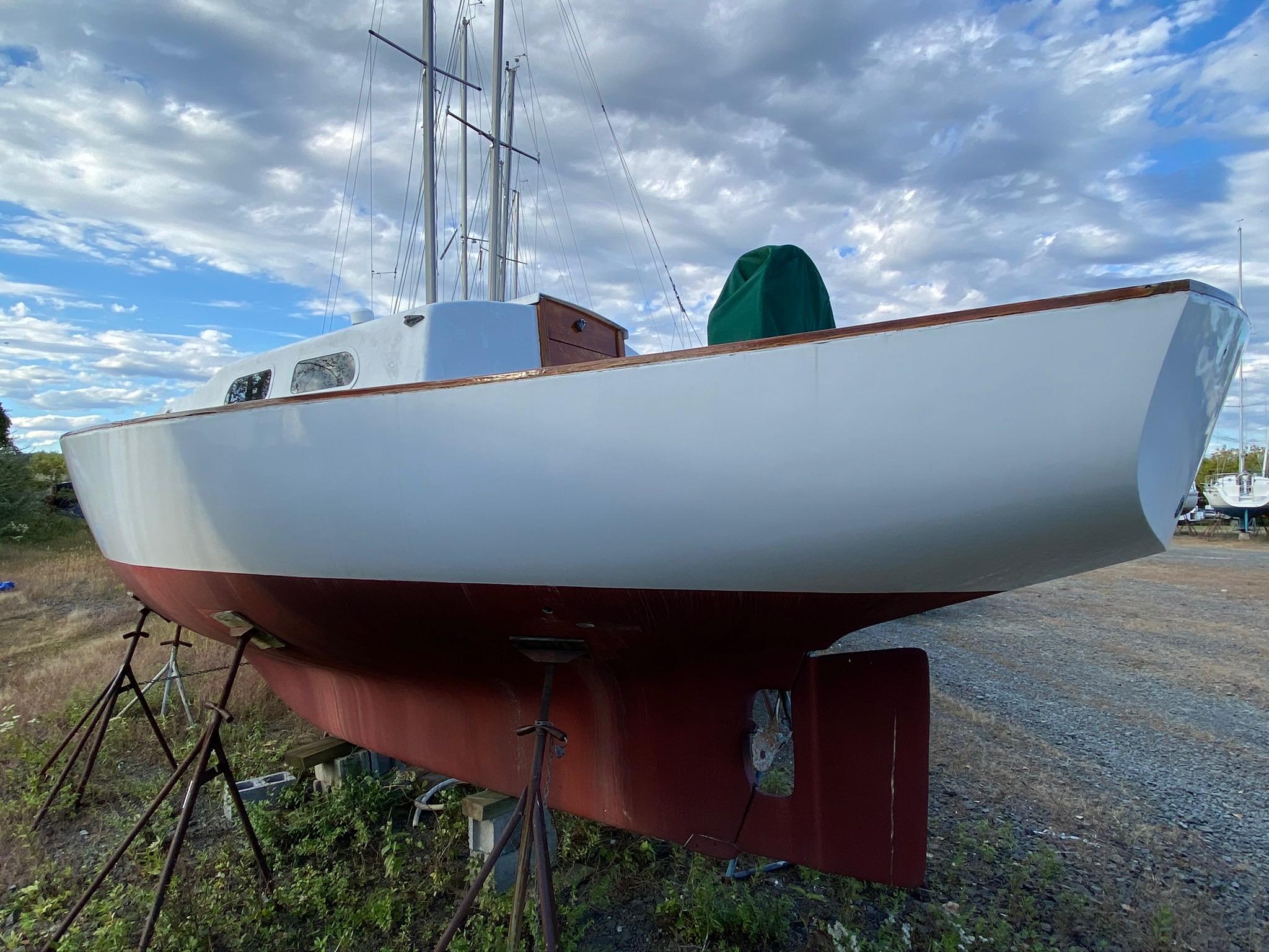 1968 Pearson Wanderer sailboat on stands under a cloudy sky.