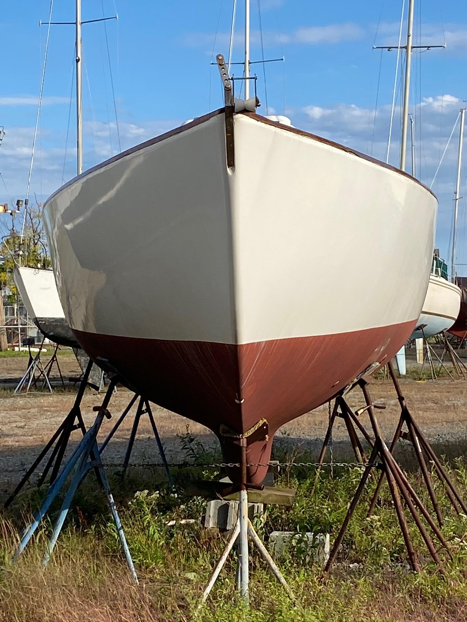 1968 Pearson Wanderer sailboat on stands, viewed from the front, with a clear blue sky.