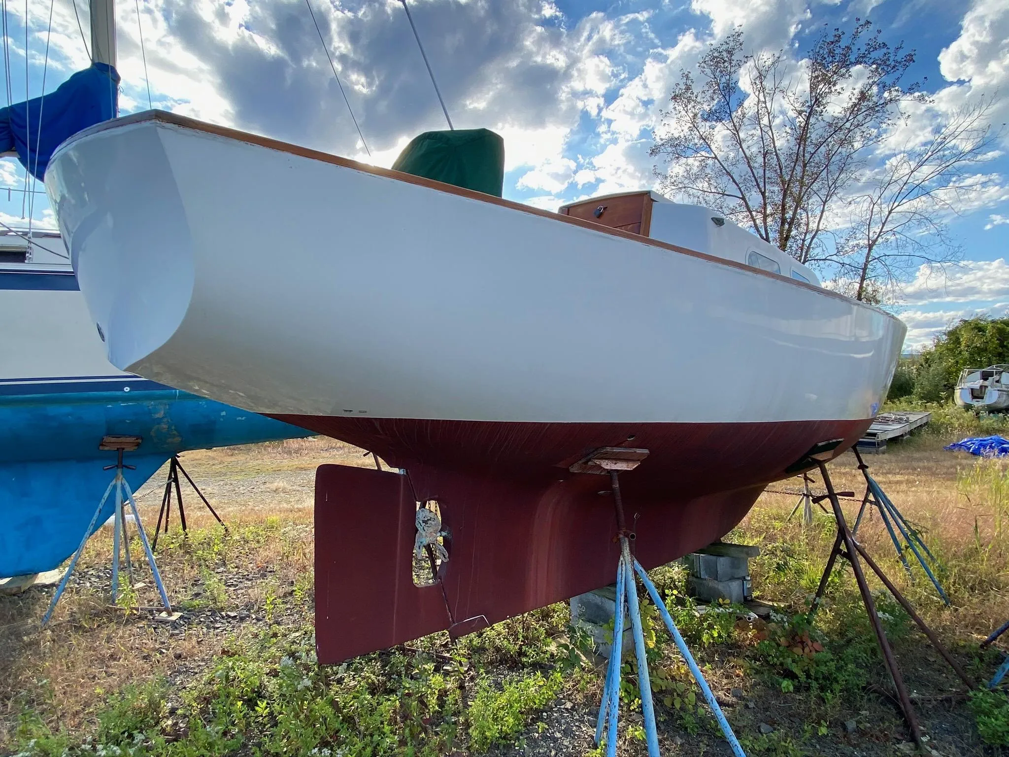 1968 Pearson Wanderer sailboat on stands, under a partly cloudy sky.