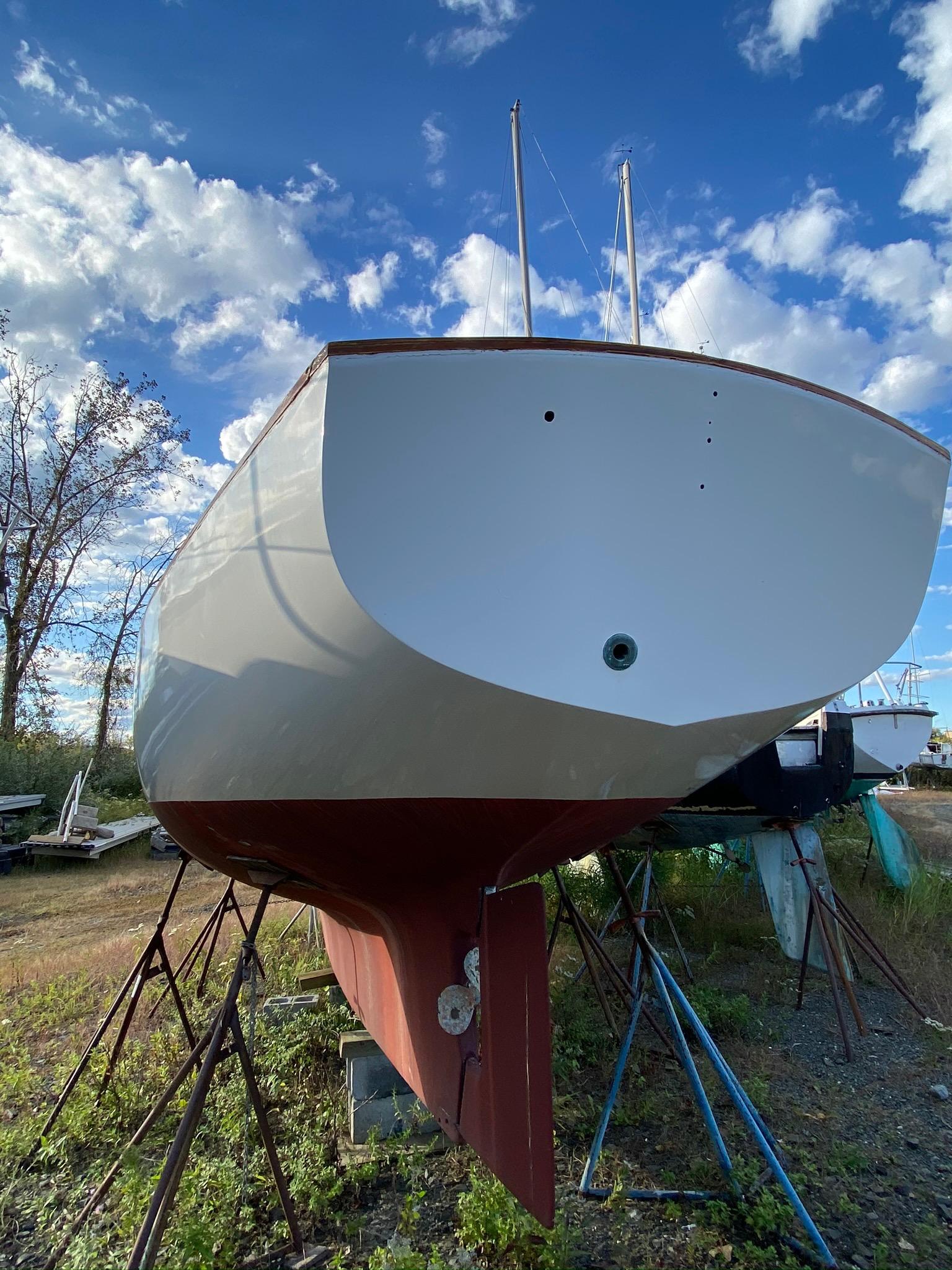 1968 Pearson Wanderer sailboat on stands, under a blue sky with clouds.