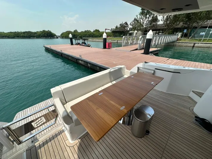  Yacht Photos Pics 2023 Ferretti Yachts 500, elegant deck with wooden table, docked by serene waters.