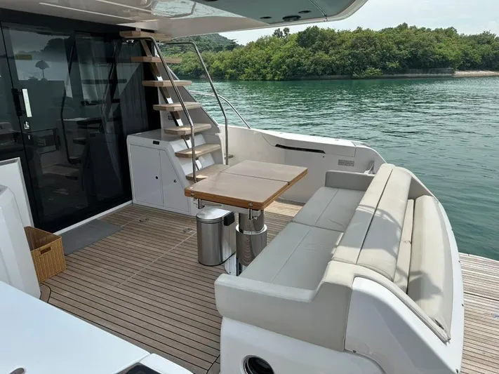  Yacht Photos Pics 2023 Ferretti Yachts 500 deck with seating, table, and stairs by the water.