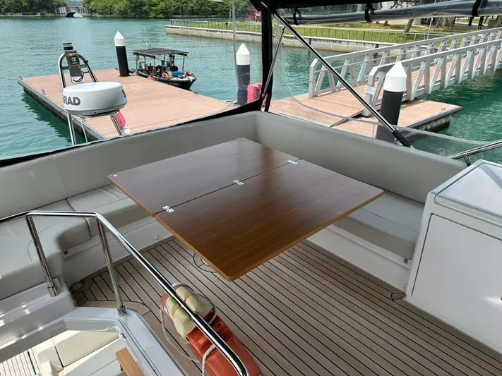  Yacht Photos Pics 2023 Ferretti Yachts 500 deck with wooden table and marina view.
