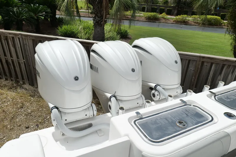  Yacht Photos Pics Triple Yamaha outboard engines on 2024 Contender 35 ST boat, docked near lush greenery.