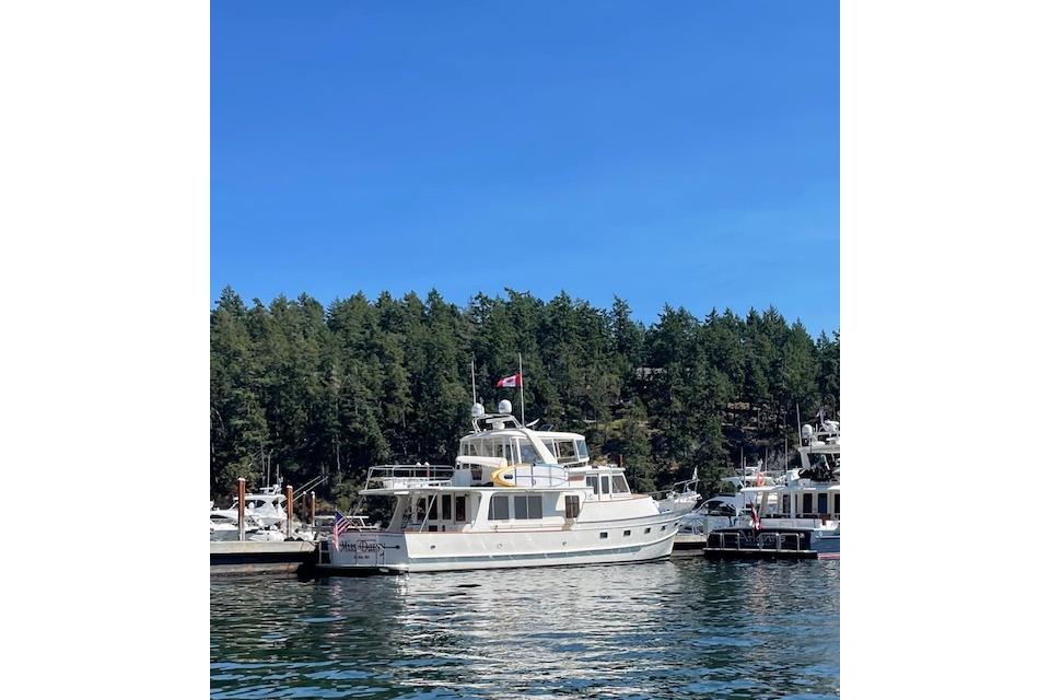 Luxury Fleming yacht docked in scenic marina, 2005 model, surrounded by lush trees.