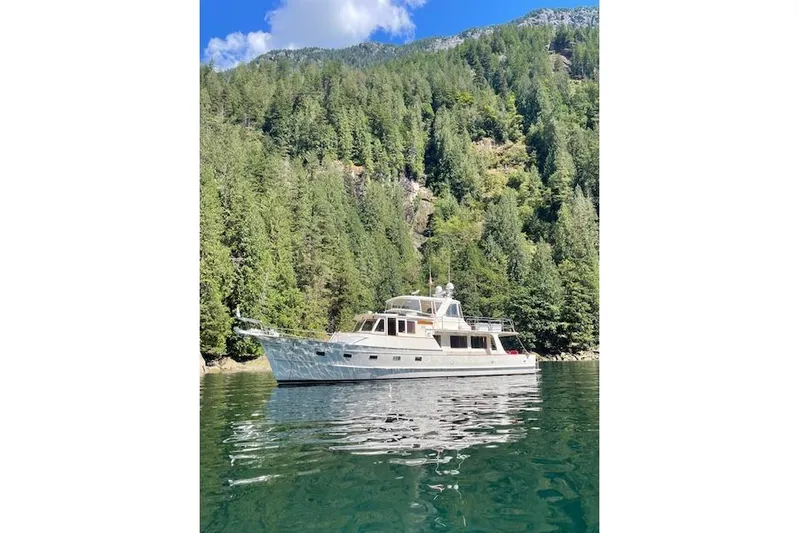 Miss Daisy Yacht Photos Pics Fleming yacht from 2005 on a serene lake, surrounded by lush green forest.