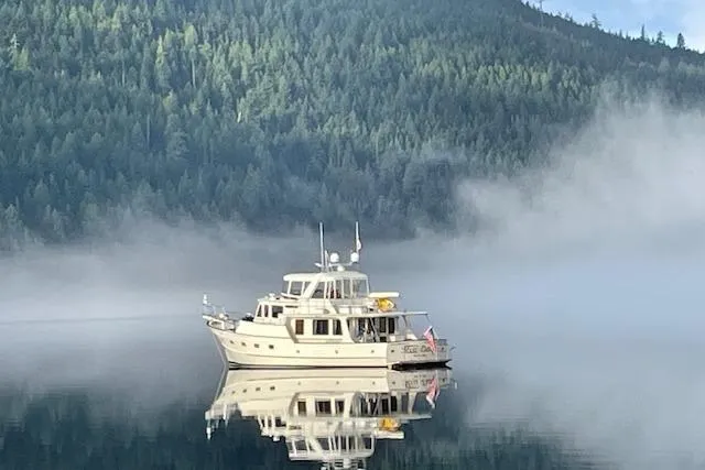 Miss Daisy Yacht Photos Pics A 2005 Fleming yacht on a misty lake, surrounded by forested hills.