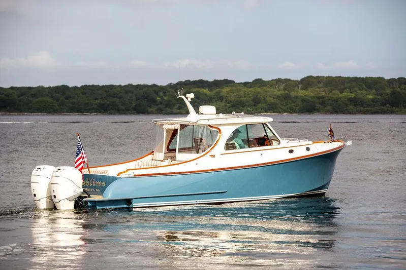 Sublime Yacht Photos Pics 2022 Hinckley 35 boat on water, blue hull, dual outboard engines, American flag displayed.