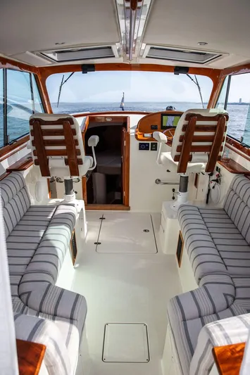 Sublime Yacht Photos Pics Interior of 2022 Hinckley 35 boat with striped seating and wooden accents, overlooking the ocean.