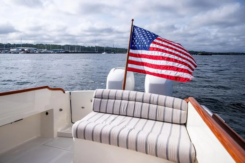 Sublime Yacht Photos Pics Hinckley 35 boat (2022) with American flag, striped seating, on a calm lake.