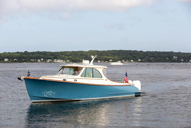 Sublime Yacht Photos Pics 2022 Hinckley 35 boat cruising on a calm lake with scenic shoreline.