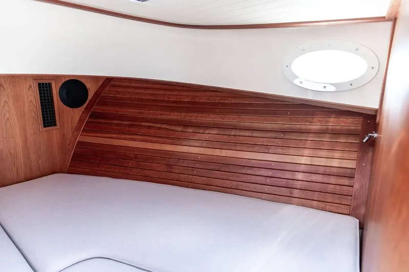 Sublime Yacht Photos Pics Interior cabin of 2022 Hinckley 35 boat with wooden paneling and round window.