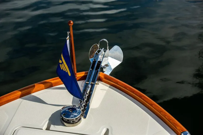 Sublime Yacht Photos Pics Bow of 2022 Hinckley 35 yacht with flag and anchor on calm water.