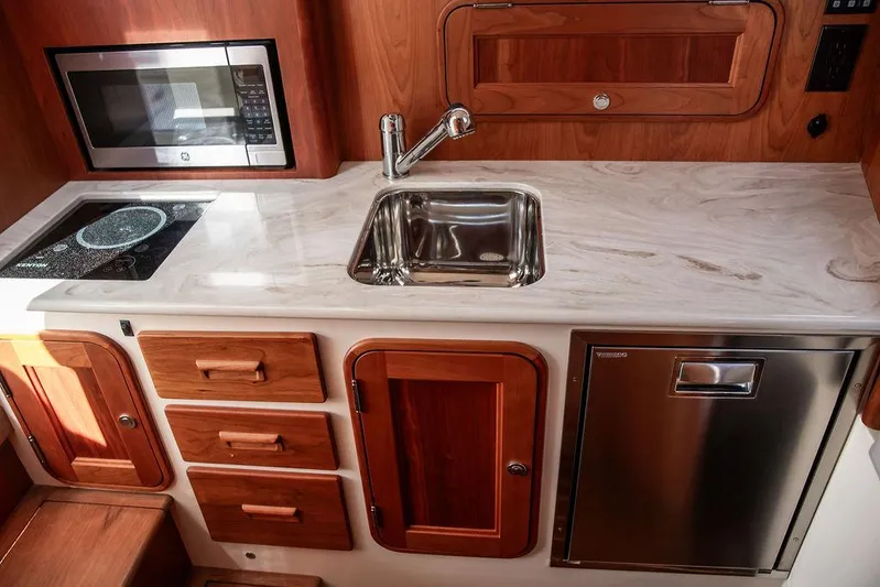 Sublime Yacht Photos Pics Modern galley kitchen in 2022 Hinckley 35 yacht with sink, microwave, and wooden cabinetry.