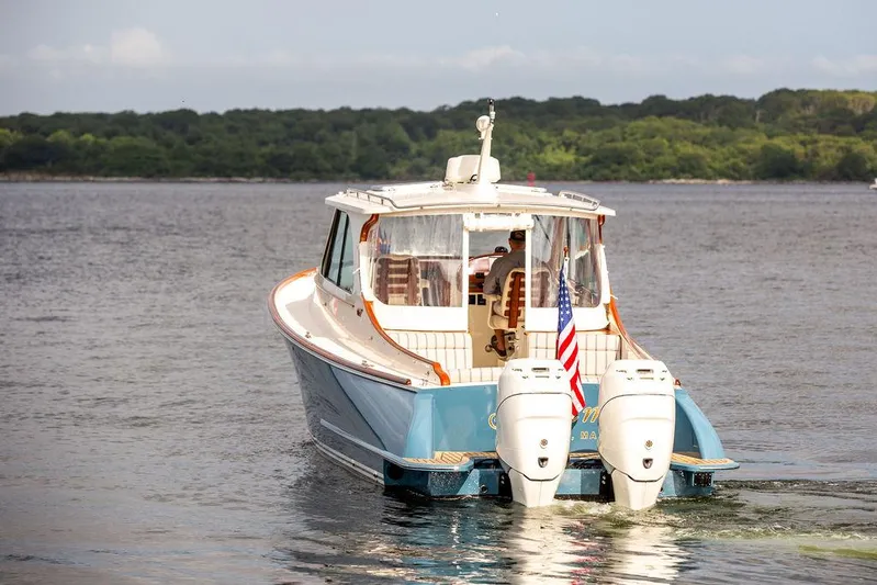 Sublime Yacht Photos Pics 2022 Hinckley 35 boat cruising on a calm lake with lush green shoreline.