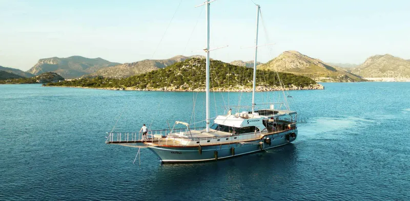  Yacht Photos Pics 2023 Gulet yacht sailing in scenic coastal waters with mountainous backdrop.