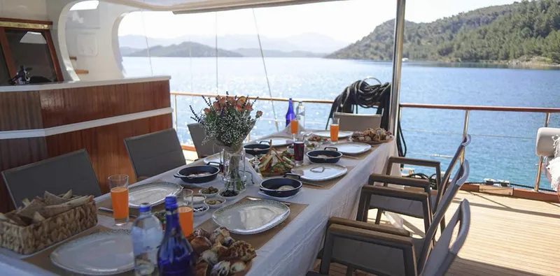  Yacht Photos Pics Luxurious dining setup on 2023 Gulet yacht with scenic ocean view.