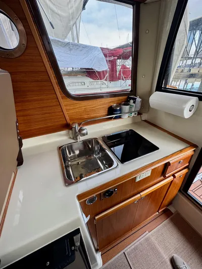  Yacht Photos Pics 2023 Ranger Tugs R-25 galley with sink, stove, and wooden cabinetry.