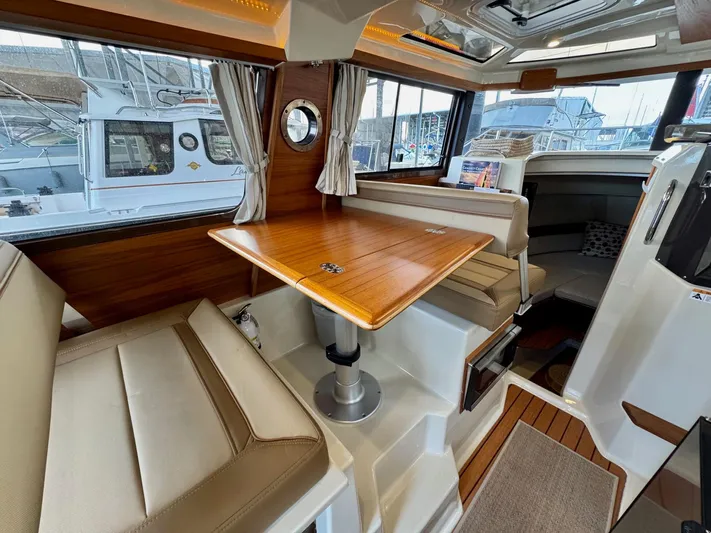  Yacht Photos Pics 2023 Ranger Tugs R-25 interior with wood table, seating, and windows.